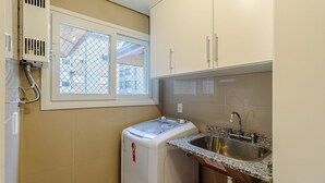 Cocina compacta con lavadora integrada, un lavabo y una ventana con vistas a edificios.