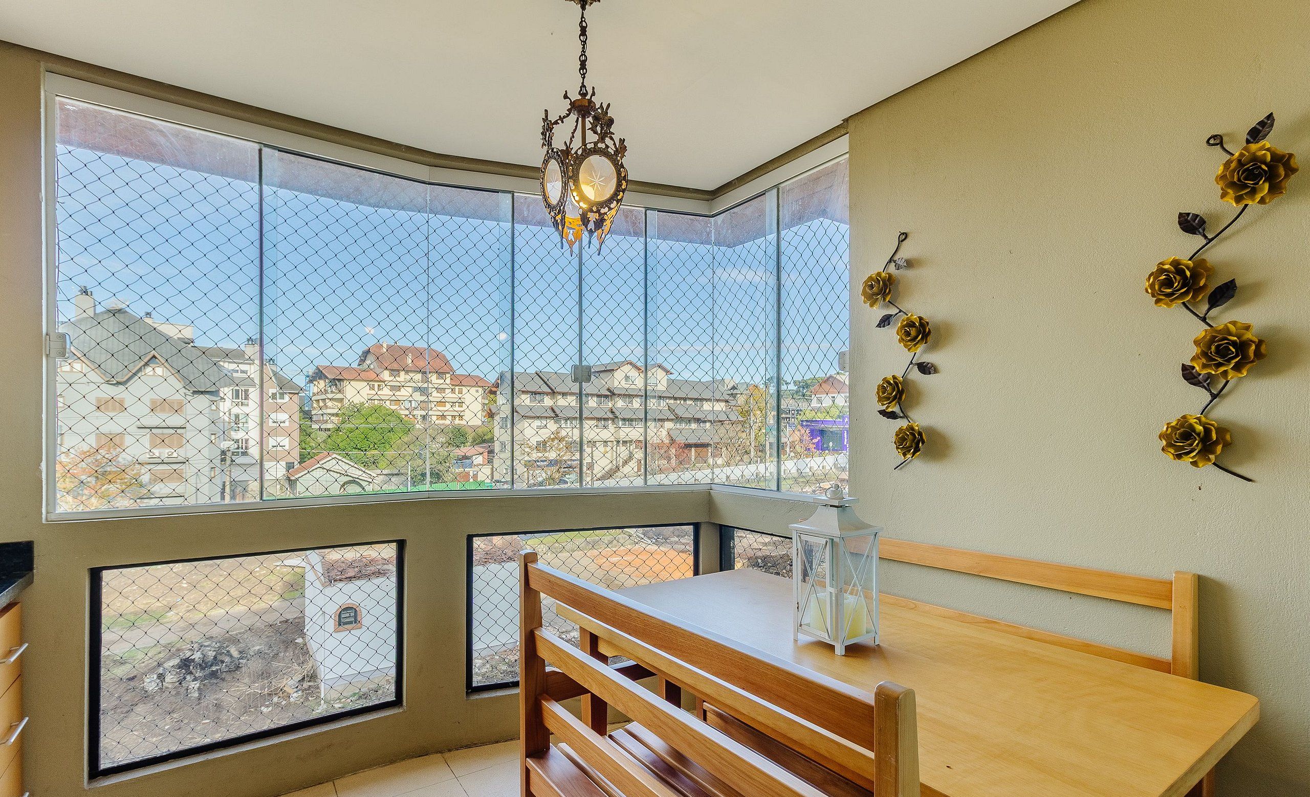 Um quarto com uma janela grande, uma mesa de madeira e um banco.