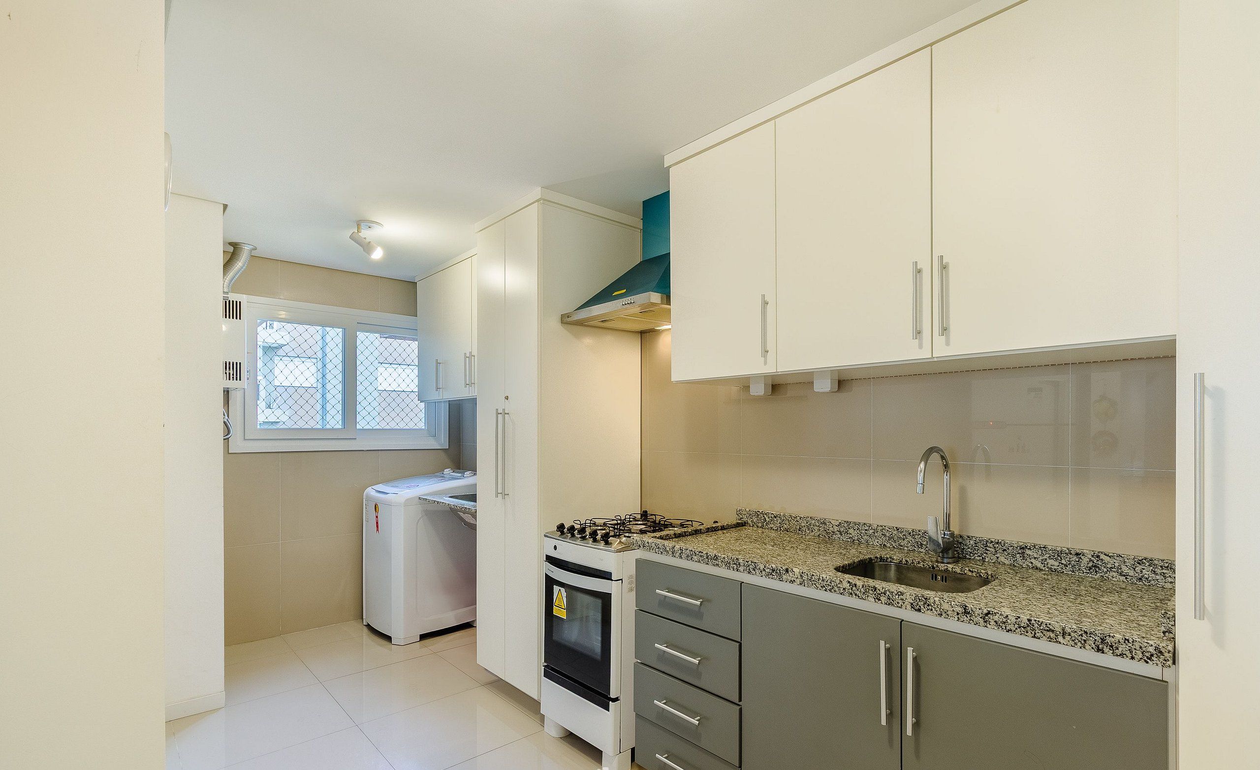A kitchen with white cabinets, a granite countertop, a stove, and a sink.
