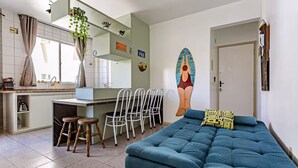 Una sala de estar moderna con un sofá azul, una zona de comedor con mostrador de cocina y un mural en la pared.