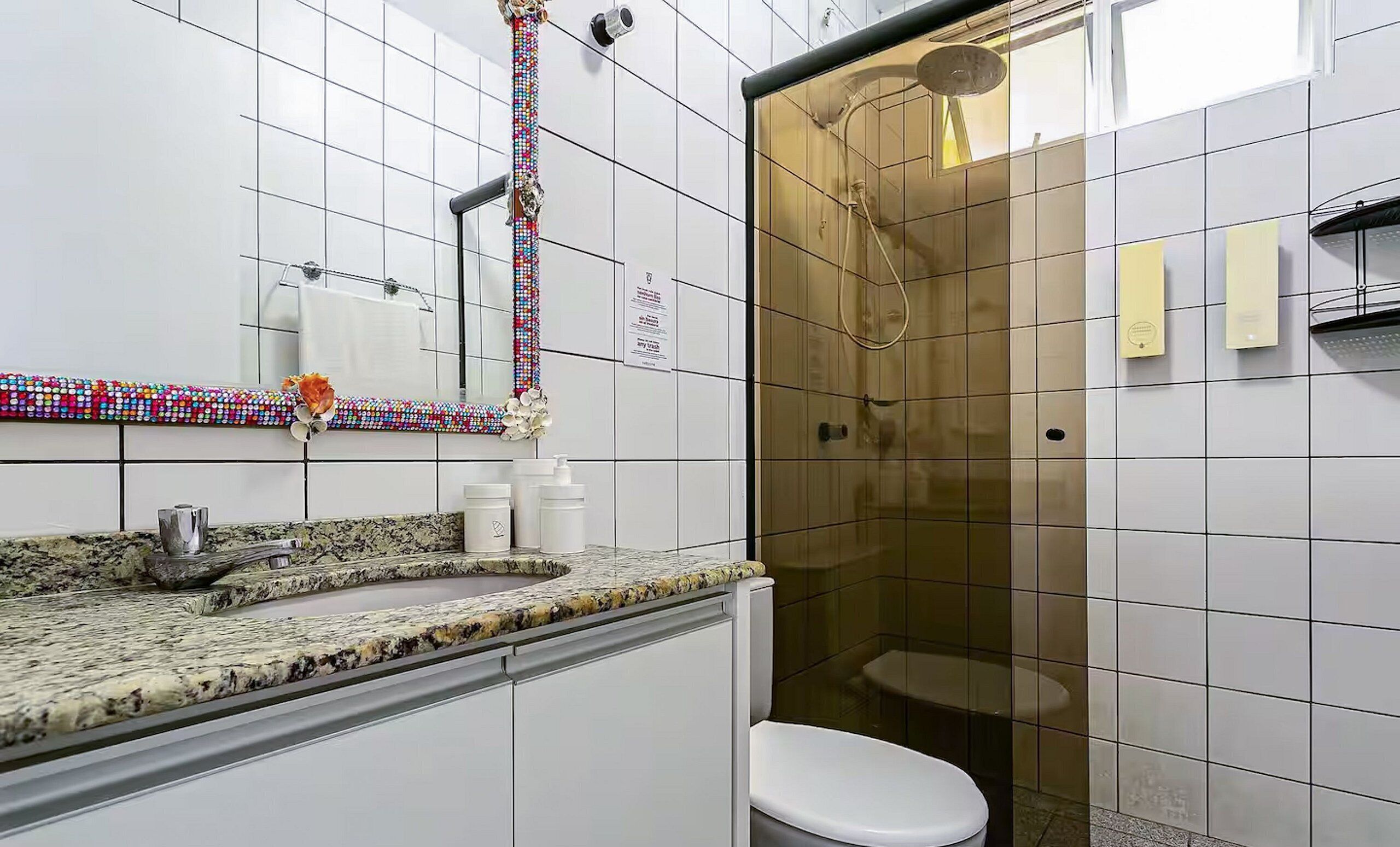 A modern bathroom with a granite countertop, a white toilet, and a glass-enclosed shower.