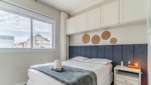 Ένα σύγχρονο υπνοδωμάτιο με κρεβάτι, κομοδίνο και διακοσμητικά έργα τέχνης στον τοίχο.