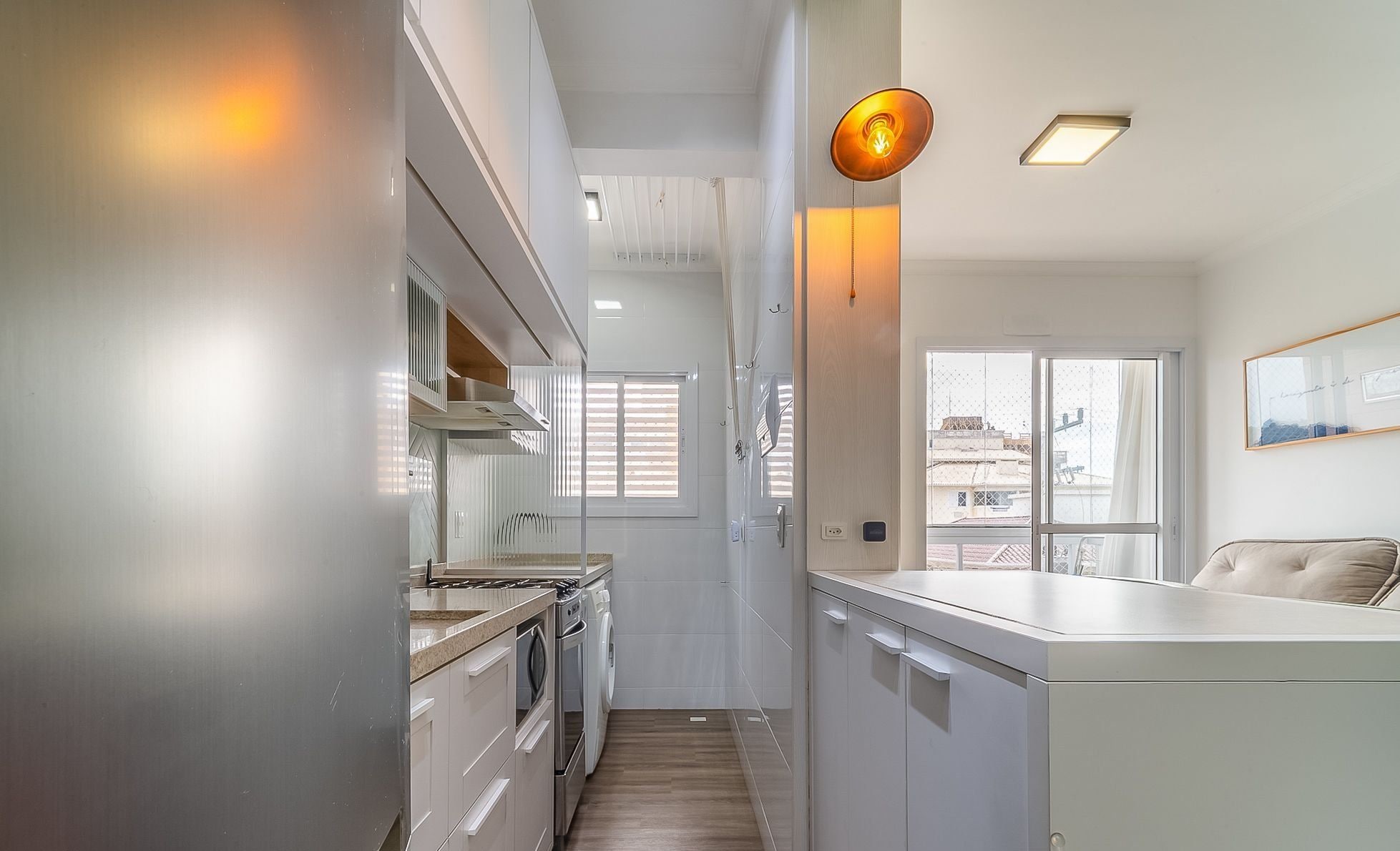 Uma cozinha moderna com eletrodomésticos de aço inoxidável, bancada de madeira e vista para a cidade através de amplas janelas.