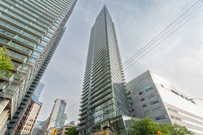 A tall, modern skyscraper with a glass facade and a pointed top, surrounded by other high-rise buildings.