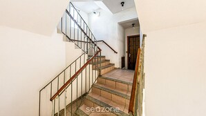 A staircase with a wooden handrail and metal balusters, leading to a room with a wooden door and a light fixture on the ceiling. - Apart With Barbecue 750 m From the Beach Bou201 (Florianópolis)
