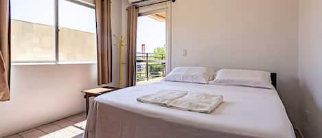 Una habitación de hotel con cama, ventana y aire acondicionado.