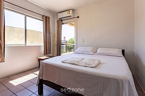 Una habitación de hotel con cama, ventana y aire acondicionado.