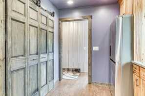 A hallway with wooden doors, a refrigerator, and a tiled floor.