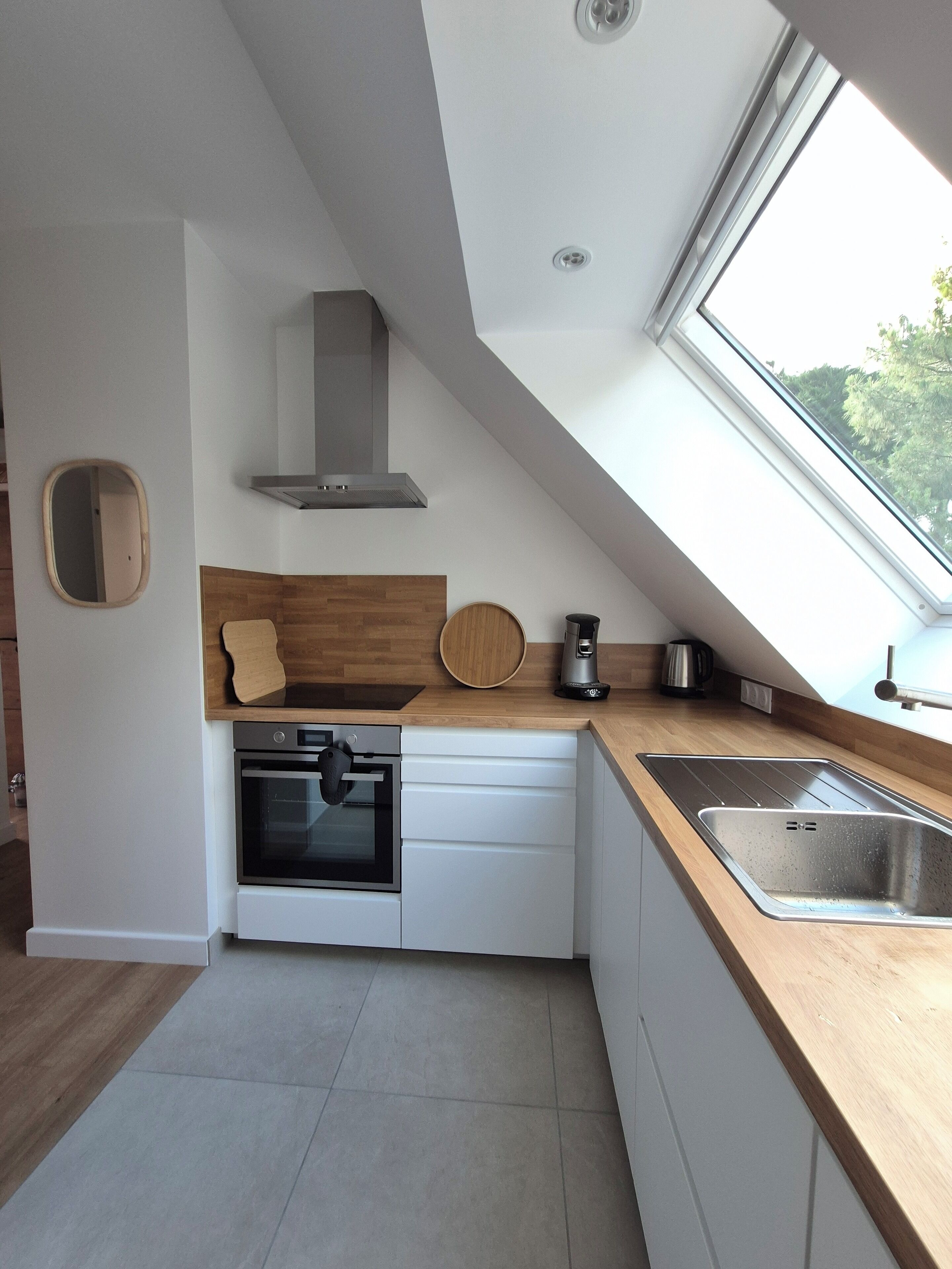 Een moderne keuken met dakraam, ingebouwde oven en een houten aanrecht.