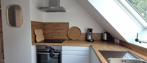 Een moderne keuken met dakraam, ingebouwde oven en een houten aanrecht.
