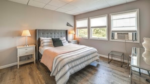 A bedroom with a bed, nightstands, a desk, and a window with blinds. - Pet-Friendly Catskills Home w/ Serene Pond! (Jefferson)
