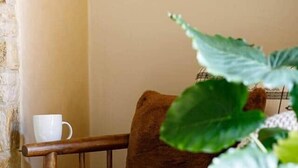 Une pièce chaleureuse avec un banc rembourré de coussins blancs, un plaid tricoté et une plante en pot.