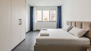 Een moderne slaapkamer met een bed, een kledingkast en een raam met gordijnen.