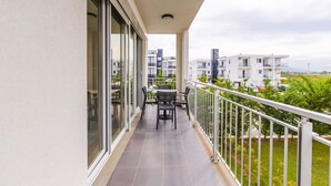 Un balcón con mesa y sillas, con vistas a una zona residencial con edificios modernos.