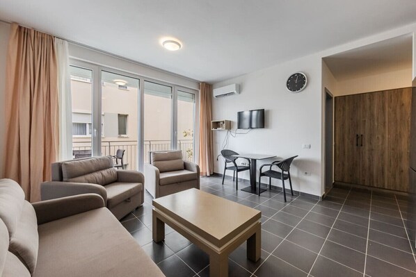A modern living room with a sofa, chairs, a table, and a TV.