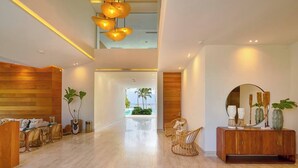 A spacious lobby with a wooden reception desk, wicker furniture, and a large mirror. - Caribbean Sea Breathtaking View Suite (Playa Juan Dolio)
