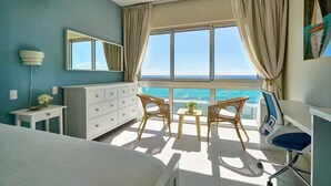 A bedroom with a large window, a bed, a dresser, a chair, and a desk. - Caribbean Ocean View, 2BDRM Beachfront Apartment (Playa Juan Dolio)