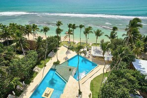 Un resort con una grande piscina, palme e vista sull'oceano.