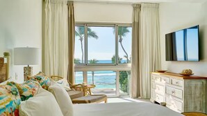 A hotel room with a bed, a desk, a chair, a TV, and a view of the ocean. - Caribbean Sunscape Beachfront Apartment (Playa Juan Dolio)