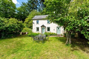 Une maison avec une pelouse, une table et des chaises, et une porte.