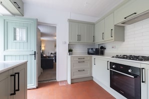 Une cuisine avec des meubles blancs, une cuisinière et un four.
