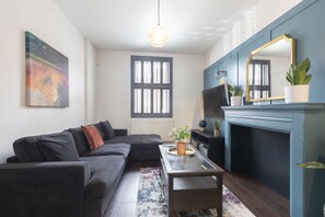 A modern living room with a sectional sofa, a coffee table, a fireplace, and a large mirror.