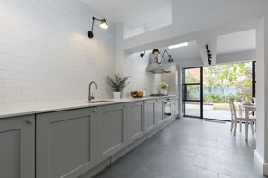 A modern kitchen with white cabinets, a large island, and a view to the outside. - Jing House - A Beautiful Two Bedroom Home (Gloucestershire)