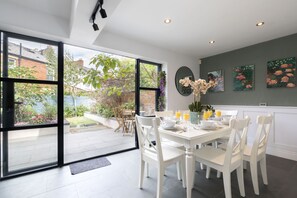 A modern dining area with a large window, white dining table, and chairs.