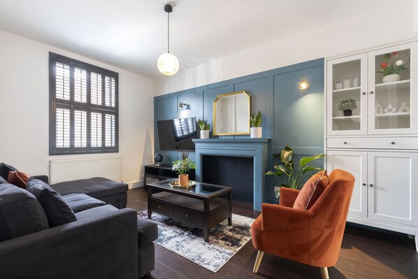 A living room with a dark sofa, a coffee table, a fireplace, and a cabinet with glass doors.