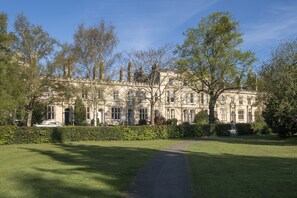 A large, historic building with a symmetrical facade, surrounded by well-maintained lawns and trees.