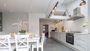 A modern kitchen with white cabinetry, a central island, and pendant lighting. - Jing House - A Beautiful Two Bedroom Home (Gloucestershire)