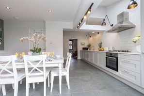 A modern kitchen with white cabinetry, a central island, and pendant lighting. - Jing House - A Beautiful Two Bedroom Home (Gloucestershire)