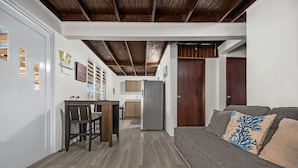 A compact living space with a kitchenette, a dining area, and a sofa with decorative pillows.