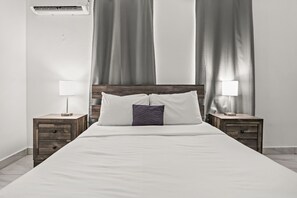 A neatly made bed with white linens, two bedside tables with lamps, and a headboard.