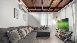 A modern living room with a sectional sofa, a flat-screen TV on a stand, and a ceiling fan.