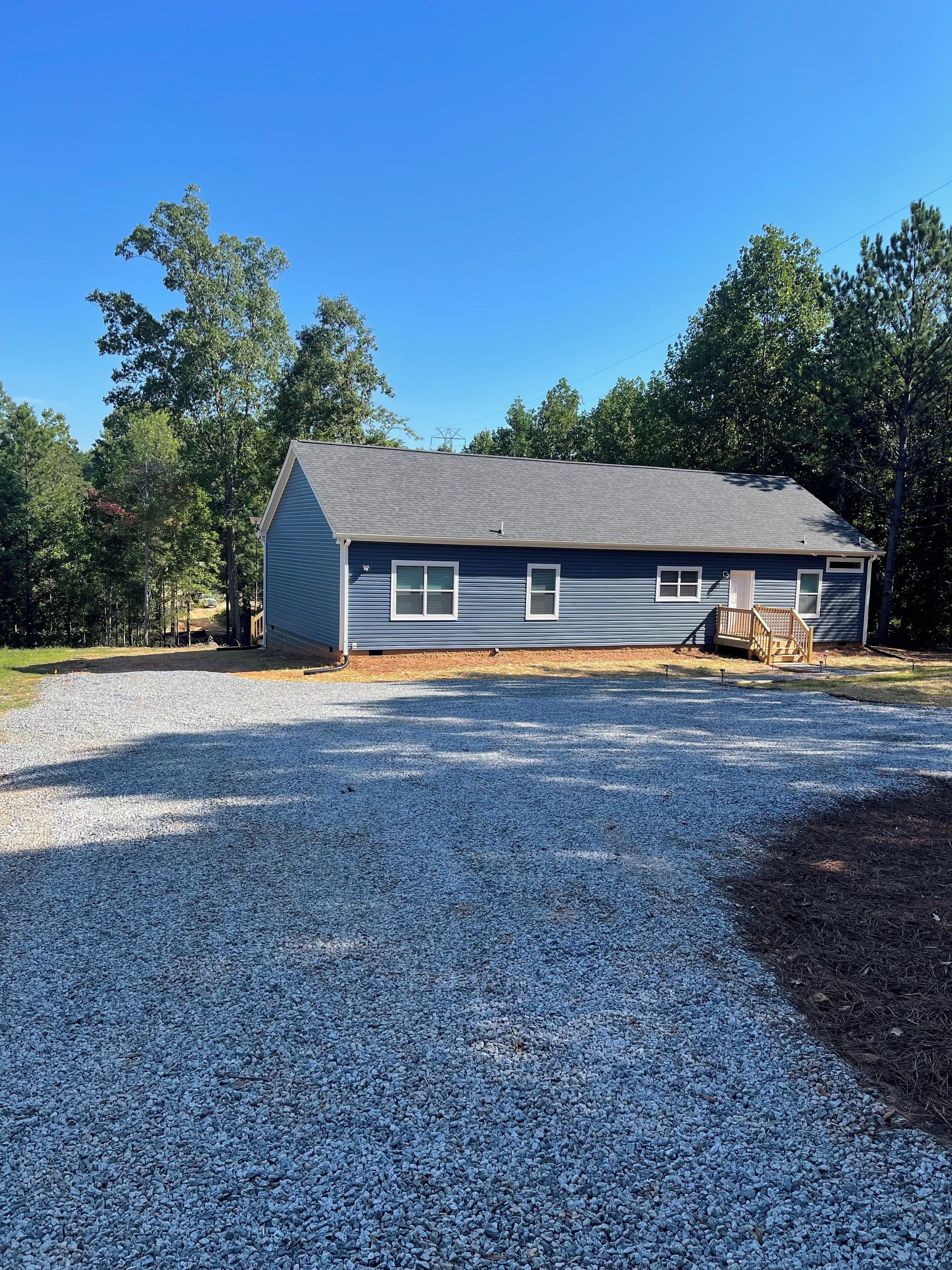 A two-story house with a gravel driveway and a wooden deck.