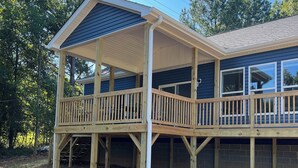 A two-story wooden house with a covered porch and a fenced deck. - Lake Norman Family Friendly Home with Dock in Denver NC (Denver)