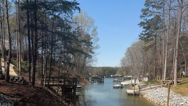 A wooden dock leading to a calm river with boats, surrounded by trees and a clear sky. - Lake Norman Family Friendly Home with Dock in Denver NC (Denver)