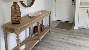 A hallway with a wooden console table, a mirror, a wall-mounted light, and a door. - Lake Norman Family Friendly Home with Dock in Denver NC (Denver)