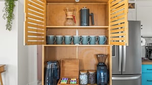 A kitchen with wooden shelves, a coffee maker, a kettle, and a coffee grinder. - Cholla Hills Home: Stunning 360° Views, Near JT (Yucca Valley)