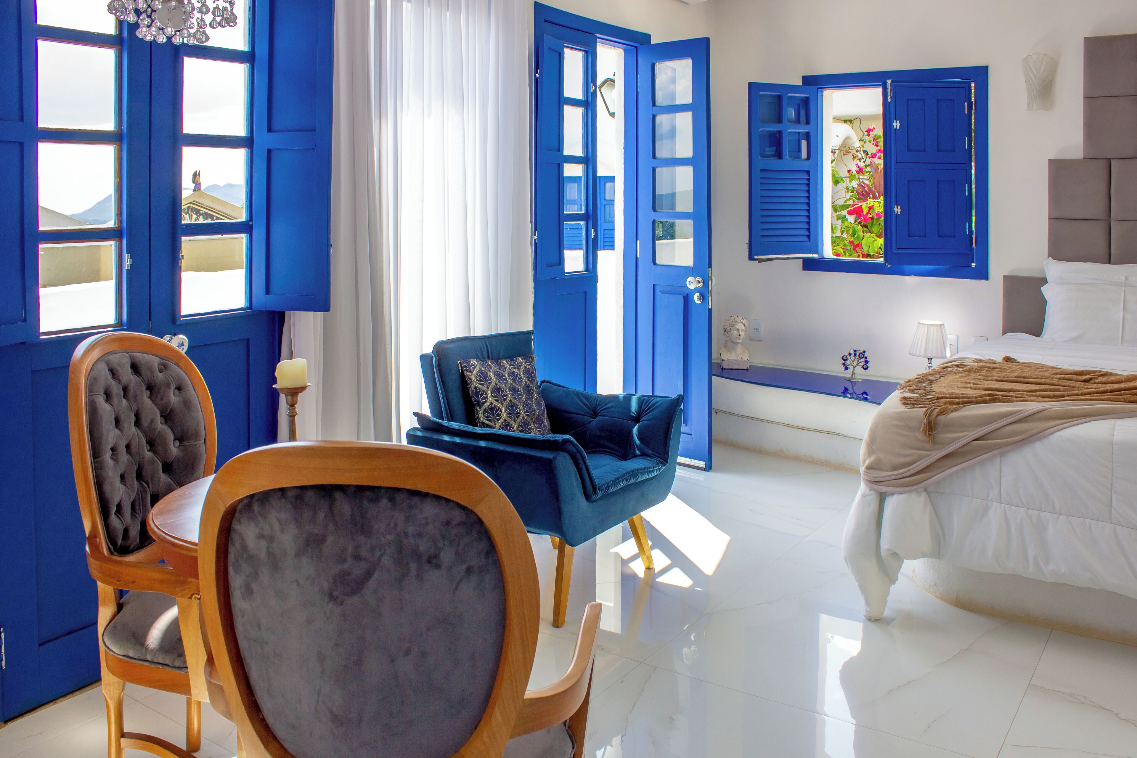 A room with a bed, a blue chair, a wooden table, and a blue door.
