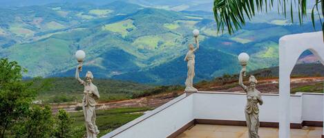 A terrace with statues and a view of rolling hills.