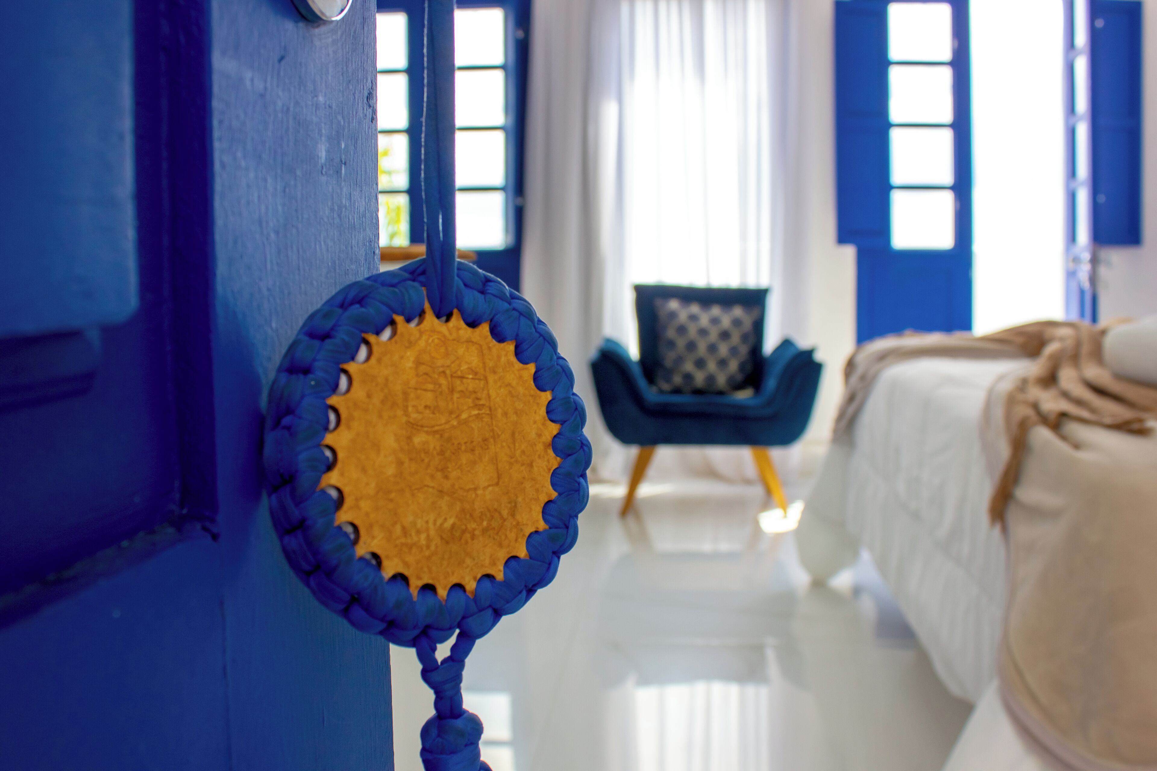 Une pièce comprenant un lit, une chaise et une porte agrémentée d’un élément décoratif bleu et jaune.