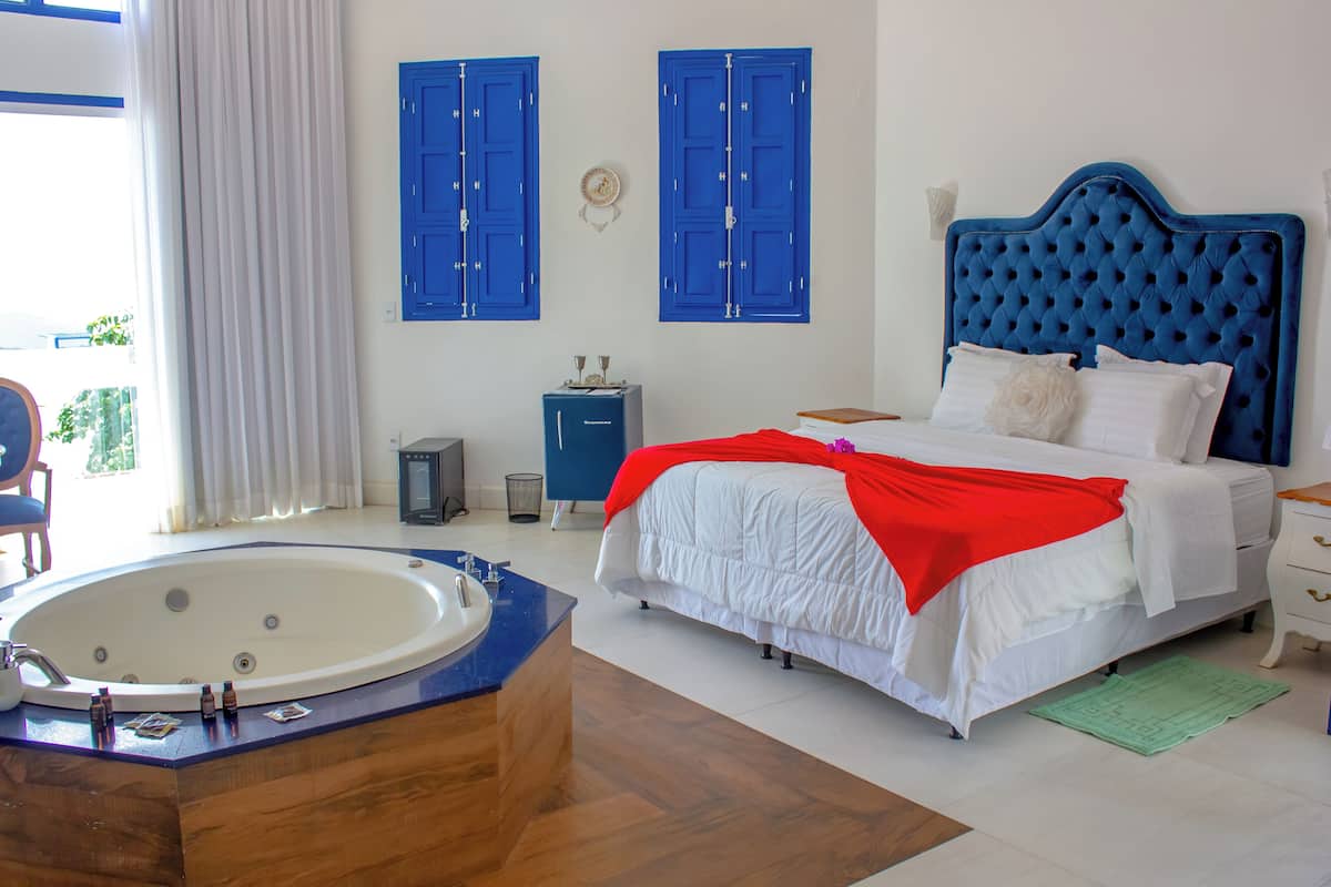 Ein Schlafzimmer mit einem großen Bett, einer Badewanne und einem Fenster mit Vorhängen.