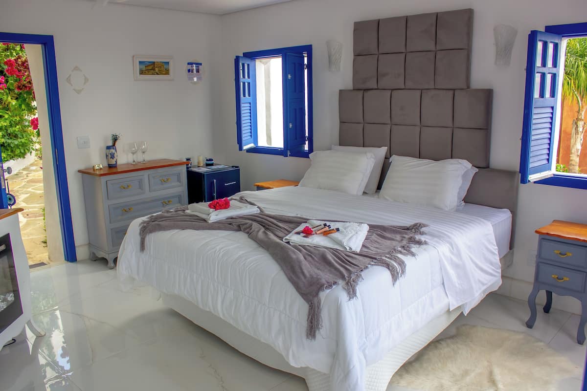 Ein Schlafzimmer mit einem großen Bett, einem Schminktisch, einem Nachttisch und einem Fenster mit blauen Fensterläden.