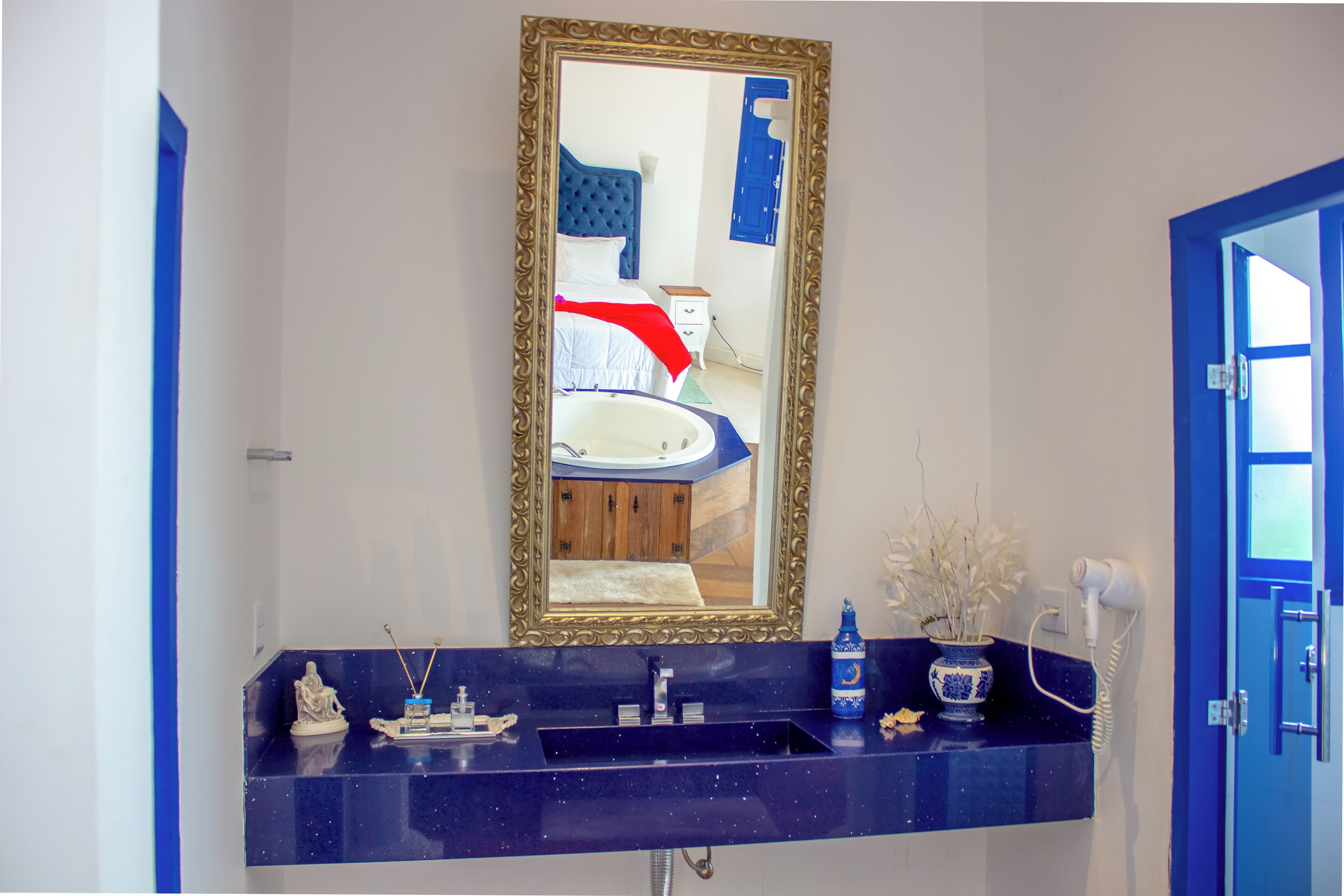Un baño con un espejo grande, un lavamanos y una puerta azul.
