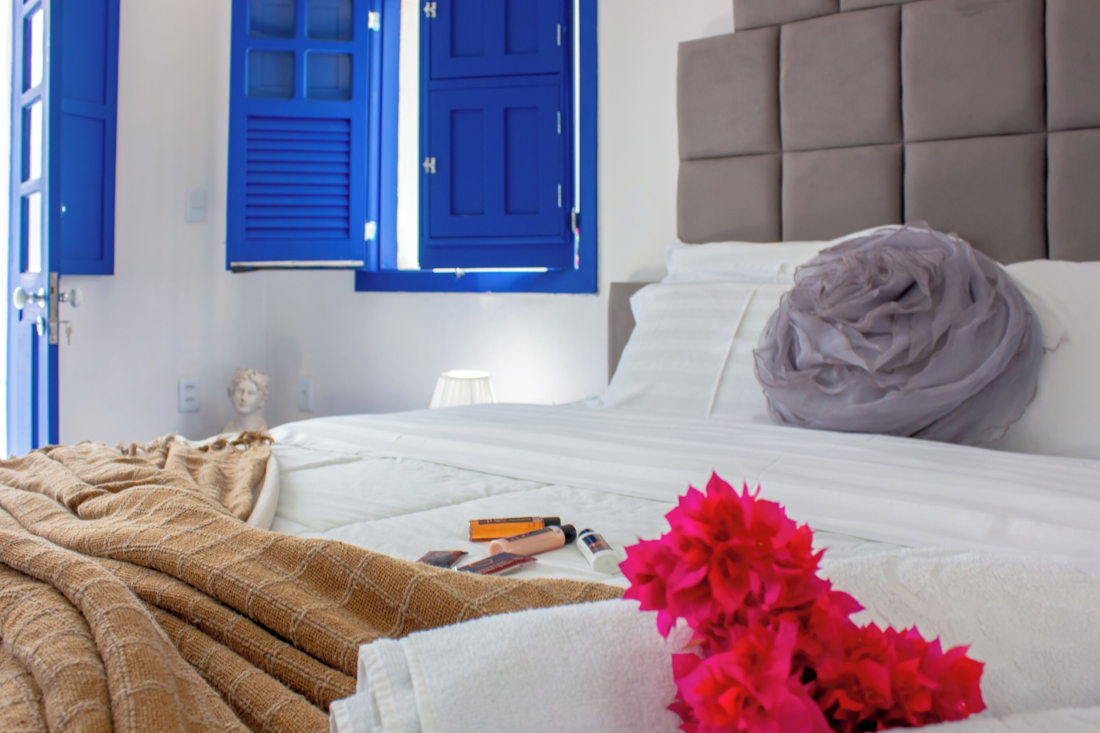 A neatly made bed with a beige blanket, a white pillow, and a decorative pillow.