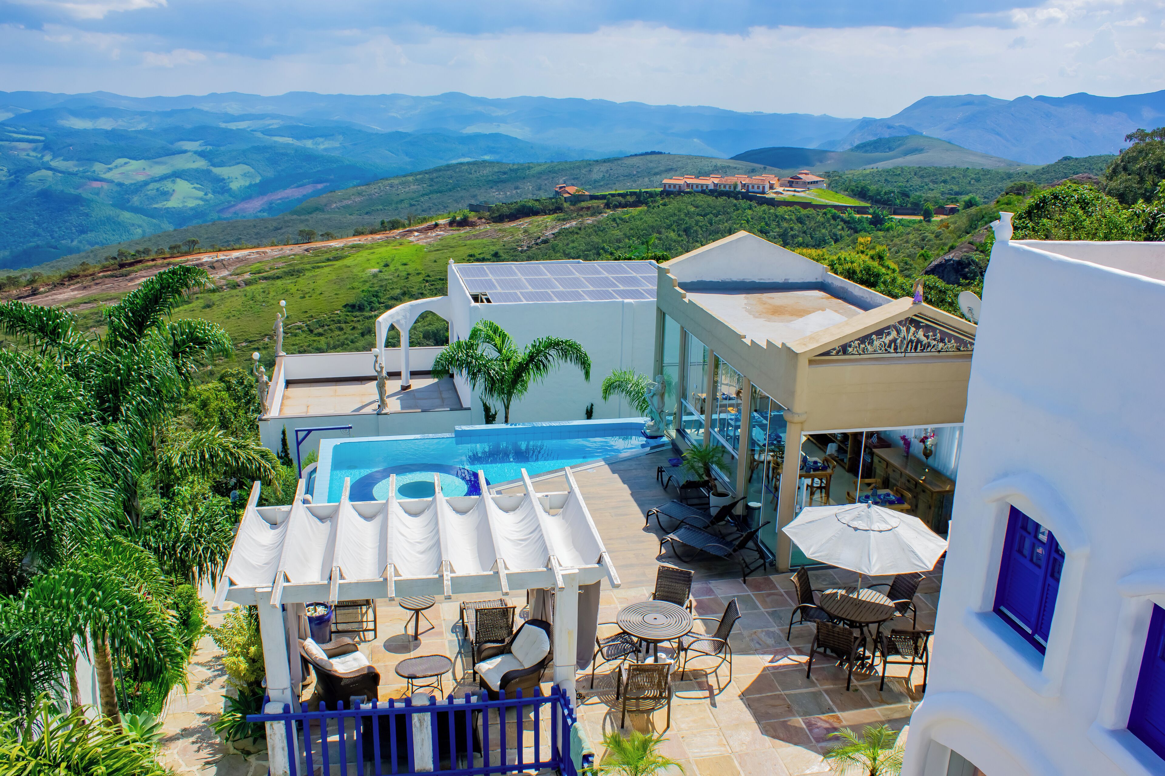 Ein Poolbereich mit Liegestühlen, einer Essgelegenheit und Blick auf die umliegende Landschaft.