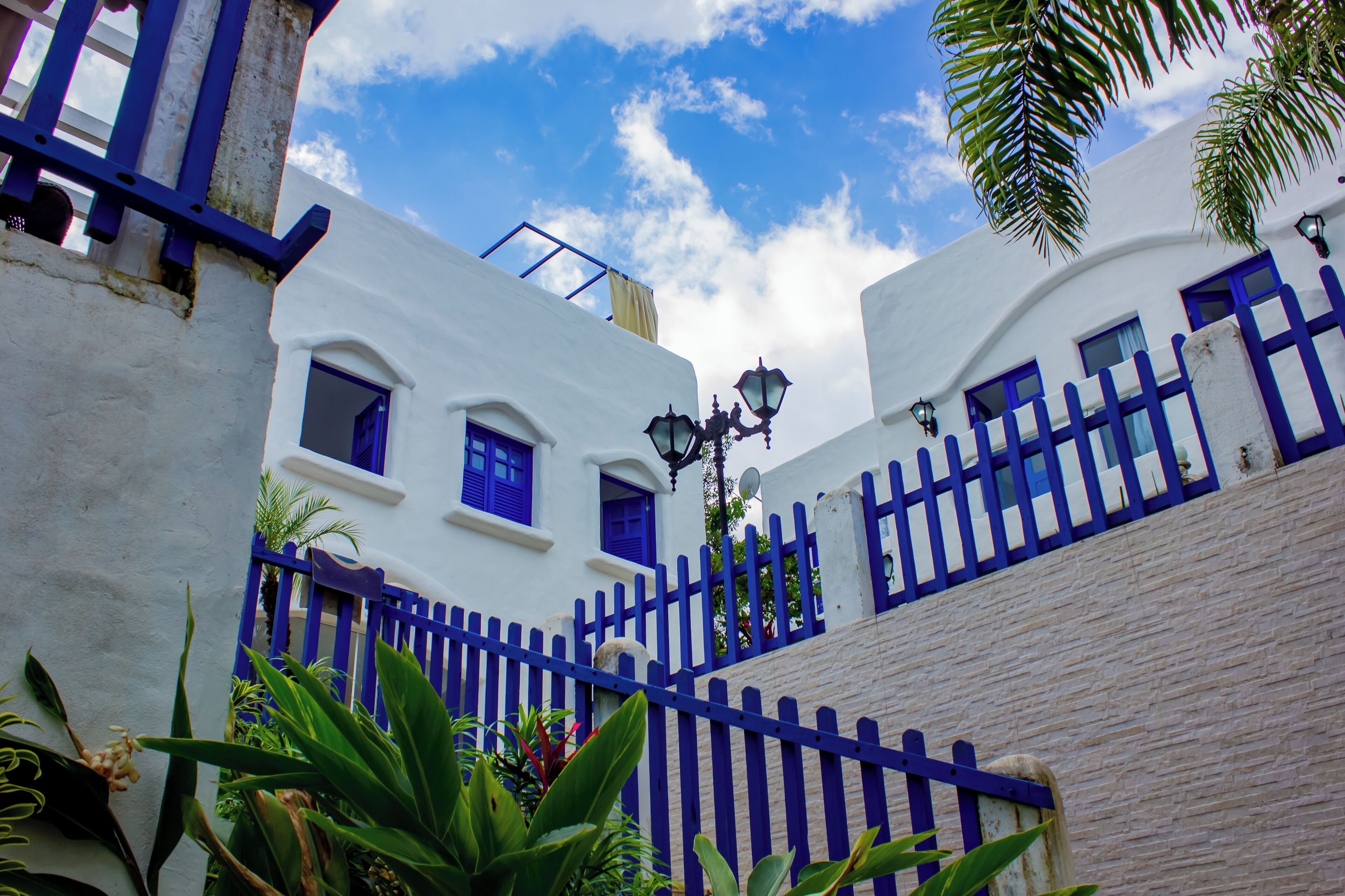 A white building with blue shutters and a blue fence.