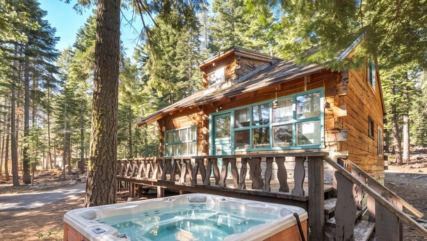 A wooden cabin with a hot tub and a deck.